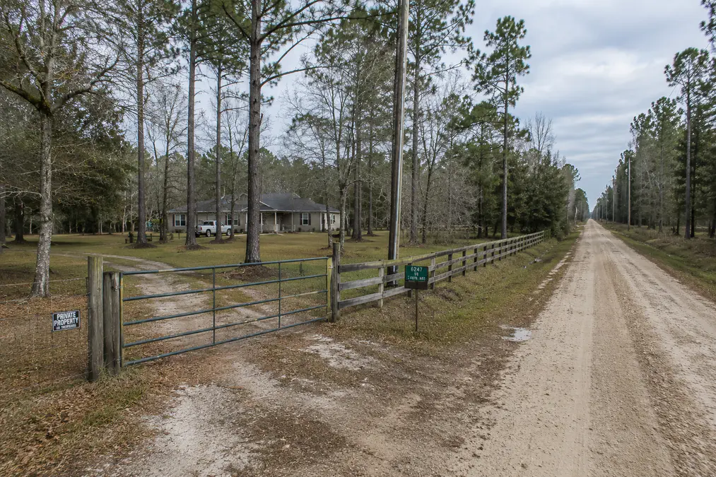 Quiet rural dirt road with fencing, trees, and access to acreage property in North Florida